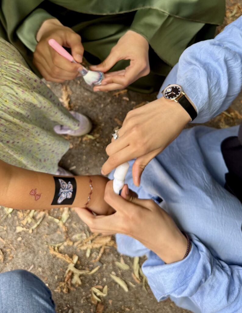 Schülerinnen verteilen kleine Tattoos.