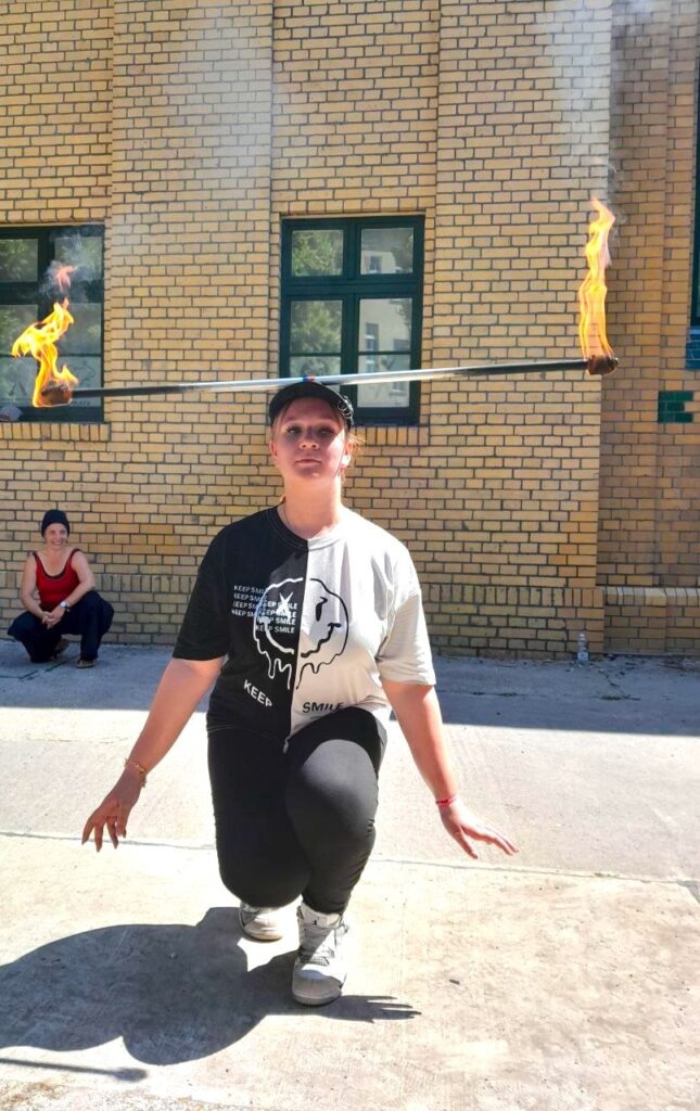 Eine Schülerin balanciert während der Feuershow eine brennende Stange auf ihrem Kopf